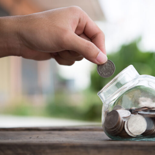 Man hands saving money into bottle for cash in future investment.